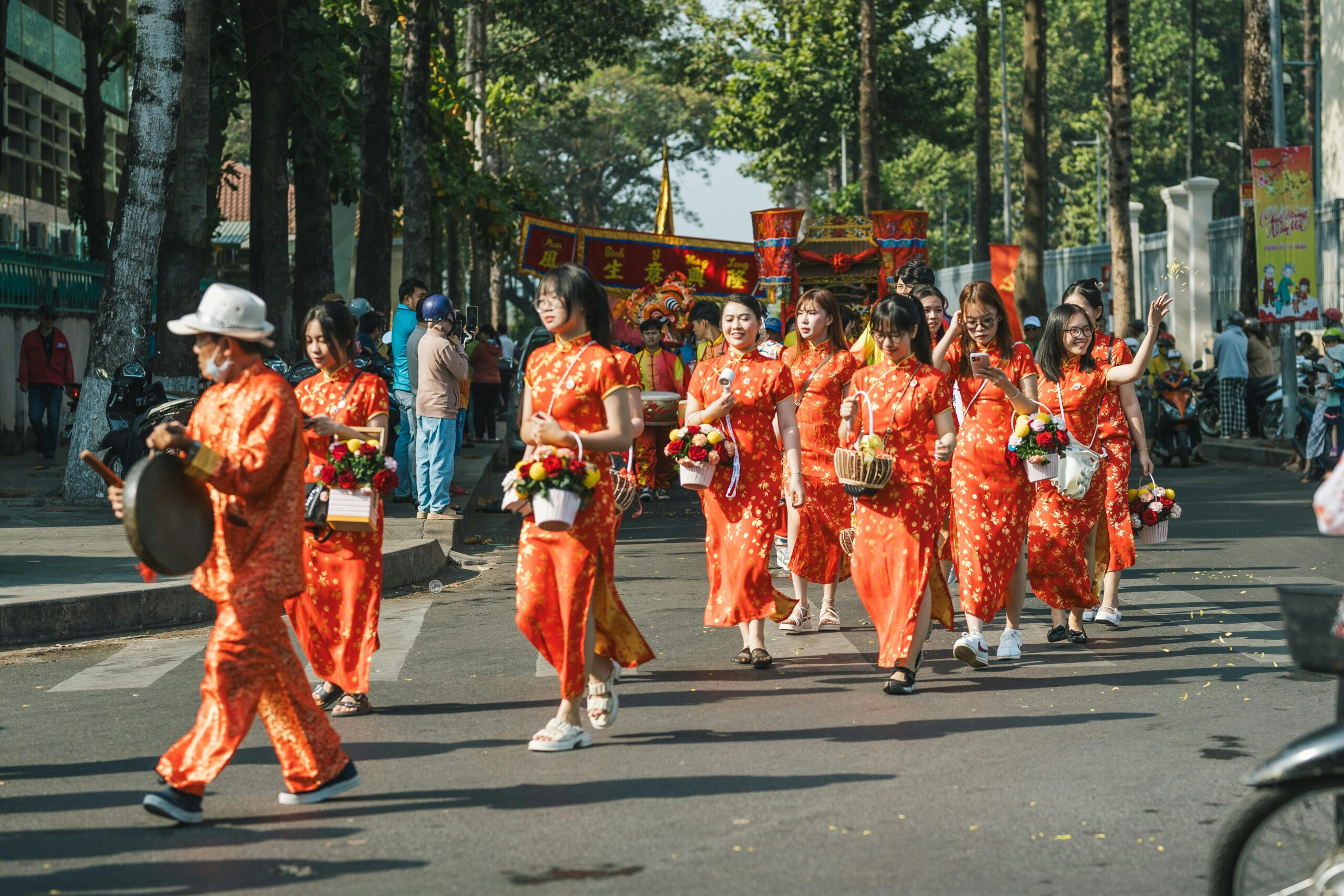 Eine Gruppe von Menschen in traditioneller Kleidung nimmt an einer asiatischen Festparade im Freien teil.