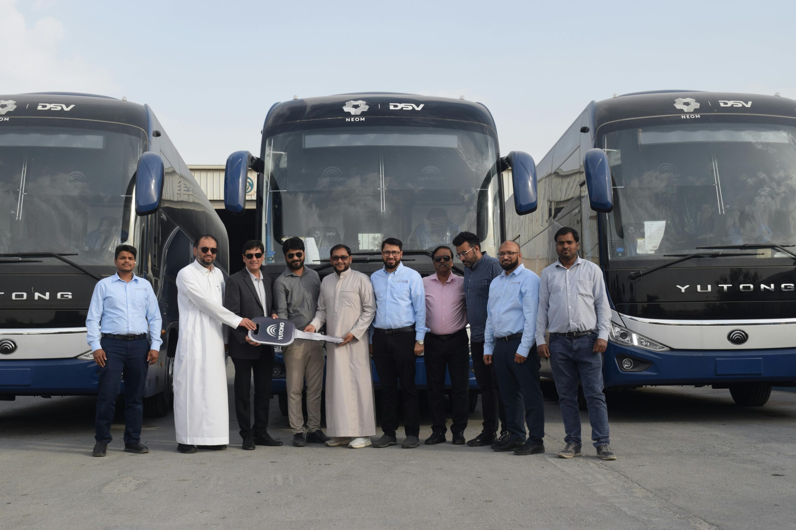 Eine Gruppe von GeschÃ¤ftsleuten posiert fÃ¼r eine Ãœbergabezeremonie vor neuen Yutong-Bussen.