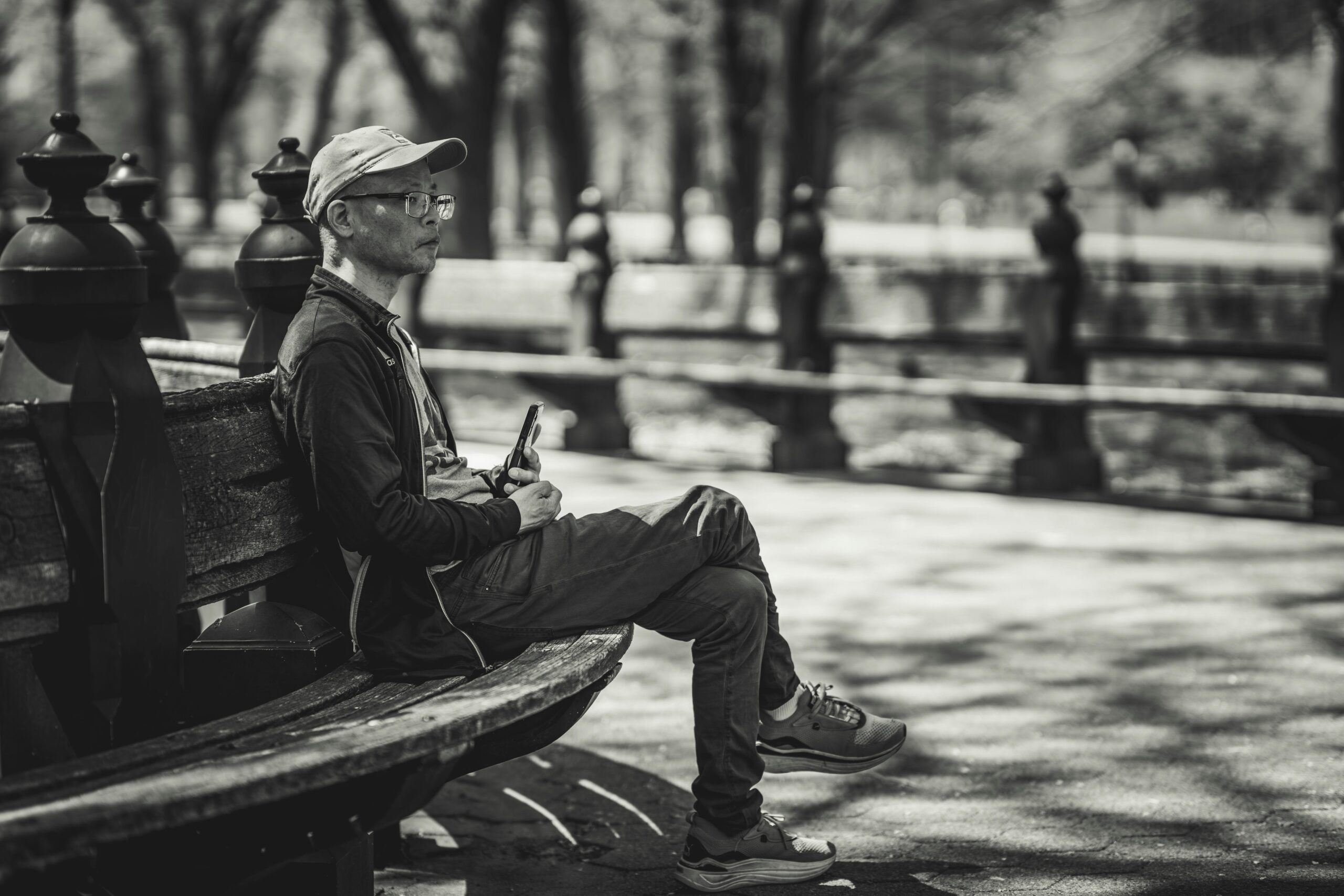 Wechseljahre bei Männern: Symptome und Ursachen die 2025 jeden treffen kann Ein Mann entspannt auf einer Bank im Central Park und fängt eine ruhige Schwarz-Weiß-Szene ein.